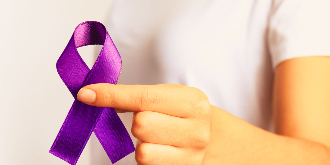 woman in a white shirt holding a purple ribbon and a banner reading Greater baton Rouge area Domestic Violence Resources